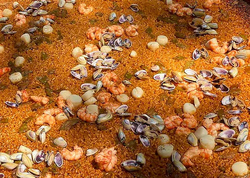 Primer plano de un arroz en la paella con gambas peladas y almejas