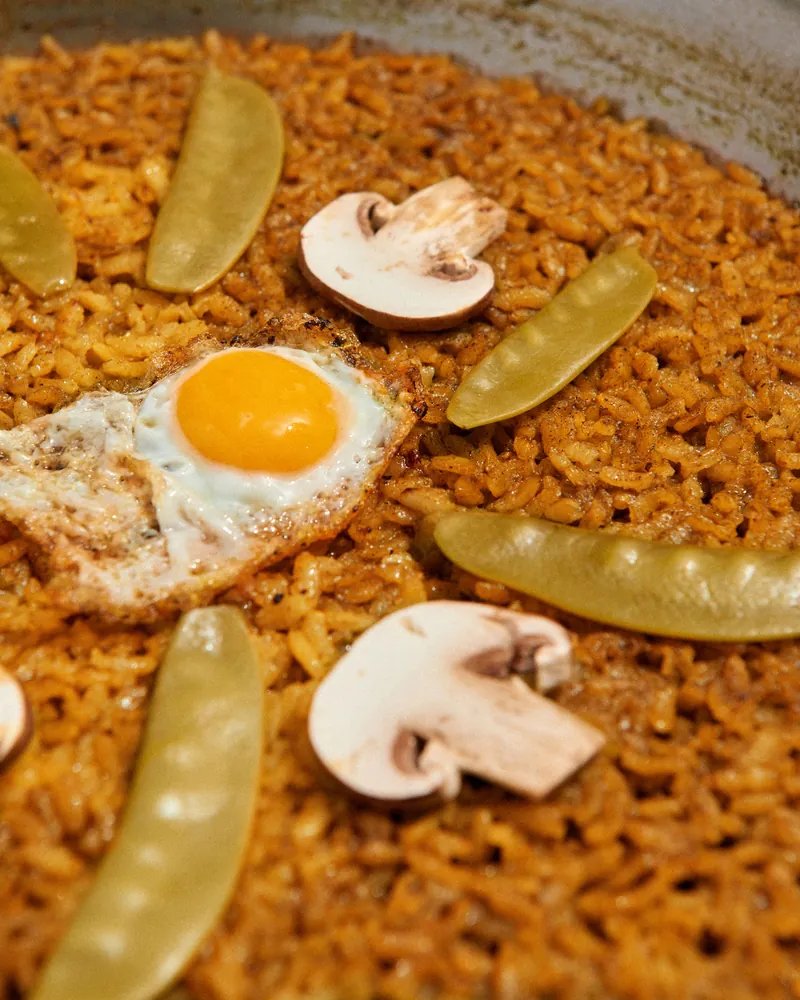 Arroz en la paella con tirabeques, champiñones y un huevo frito por encima
