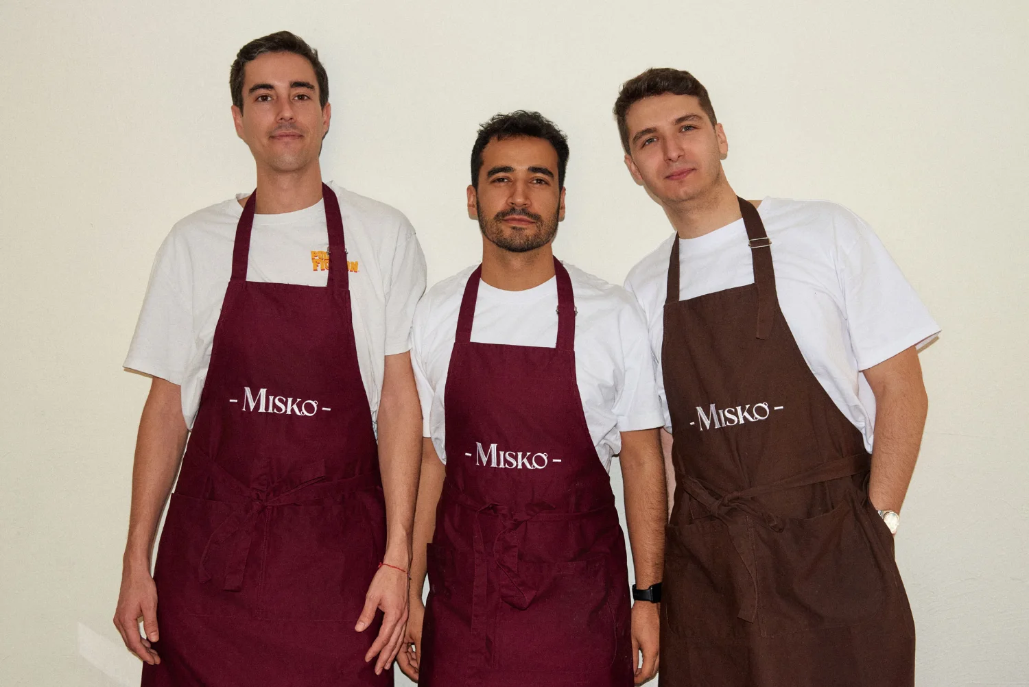Los tres amigos de Misko con sus delantales, riéndose en el estudio