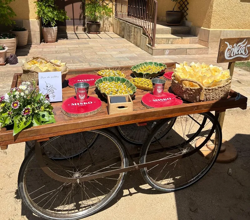 Carrito de madera con ruedas de bicicleta, con gildas, cucuruchos de patatas y un ramo de flores