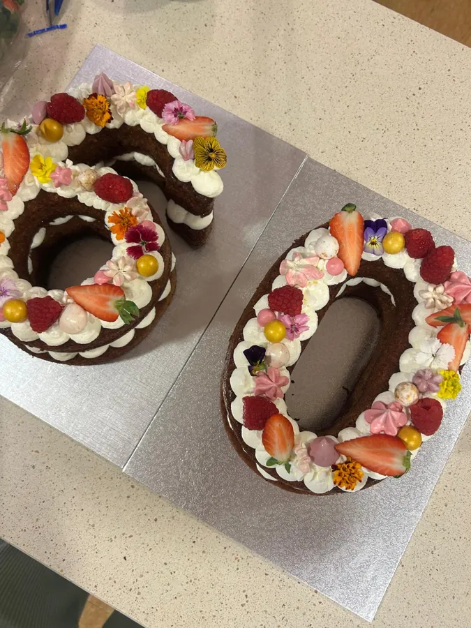 Tarta con forma de número 60, con nata, fresas, frambuesas y flores comestibles